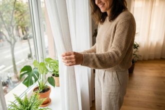 Femme ajustant des rideaux colorés dans un salon moderne