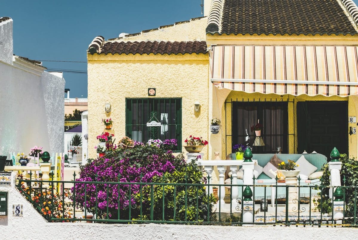 brown and white concrete house with purple flowers on the window